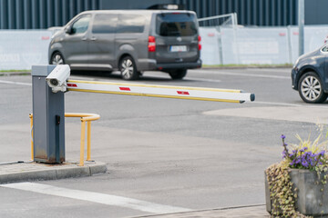 Automatic parking barrier gate in lowered position at vehicle entrance with cars visible in...