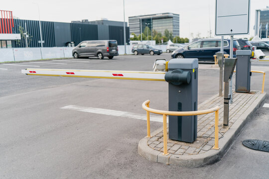 Automatic barrier gate at parking lot entrance with security system and protective railing, representing access control, vehicle management and modern urban infrastructure technology