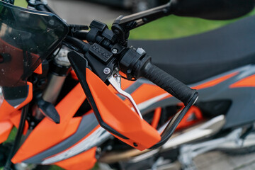 Fototapeta premium Motorcycle handlebar with hand guard and brake lever detail, representing motorbike safety gear, riding accessories, protective equipment and essential motorcycle components for riders