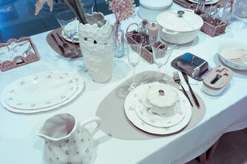 Served table with white tablecloth, plates, glasses and vase in showroom in exhibition hall store