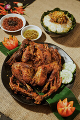 Spicy Taliwang Chicken served with warm white rice, chili sauce, fried onions, tomatoes, and cucumbers. Traditional Lombok dish (3)