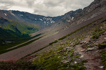 Rocky mountain pass opening to lush green valley beyond