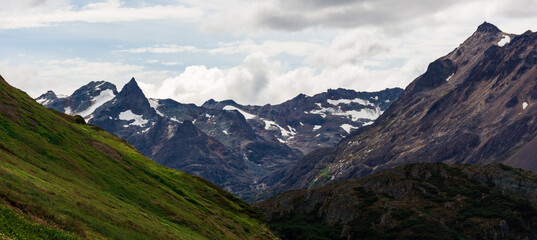 Difficult mountain trail bordered by snow and hardy shrubs