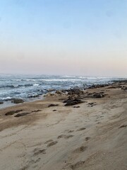 Ocean waves crashing on a sandy beach at sunset with a pastel sky