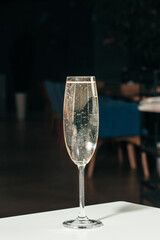 A tall glass of sparkling champagne with rising bubbles on a blurred background