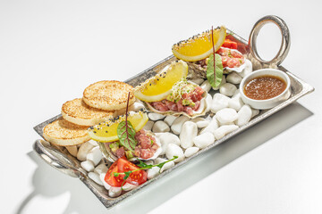 Fresh tuna tartare with lemon, greens, and crispy bread on a decorative tray