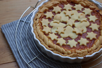 Close-up of homemade peach pie or tart on gray and white striped napkin on wooden table  