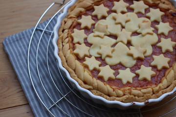 Close-up of homemade peach pie or tart on gray and white striped napkin on wooden table  