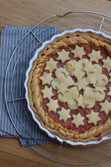 Top view of homemade peach pie or tart on gray and white striped napkin on wooden table  