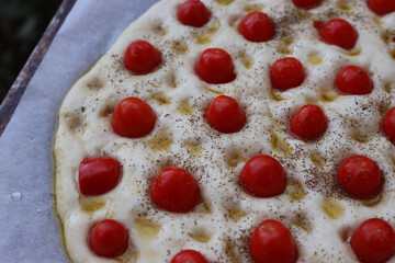 Not baked italian traditional Focaccia with red cherry tomatoes and thyme herb background