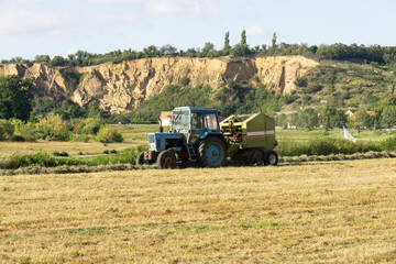 Obraz premium A tractor in the field harvesting hay. 