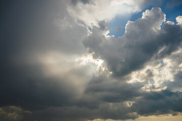 Sunbeams filtering through a dramatic cloudscape create a breathtaking interplay of light and shadow, showcasing the vastness of the sky and evoking a sense of peace and inspiration