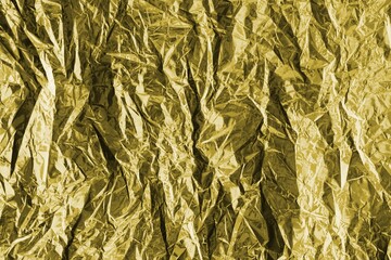 Golden crumpled foil texture on flat surface