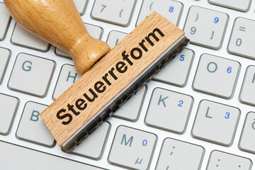 Ein Holzstempel ist beschriftet mit Sozialreform über einer Computer Tastatur als Symbolbild für...