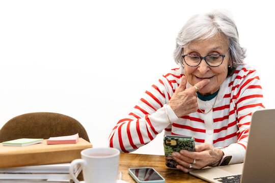 Senior woman using laptop and smartphone at home