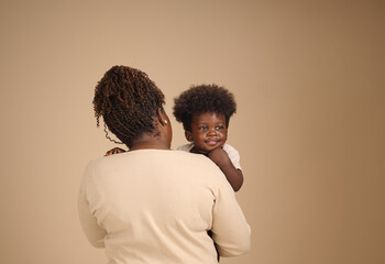 A caring mother holds her toddler over her shoulder, symbolizing warmth, nurturing, and family bonding.