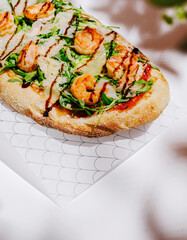 Delicious seafood flatbread topped with shrimp and arugula served on a table