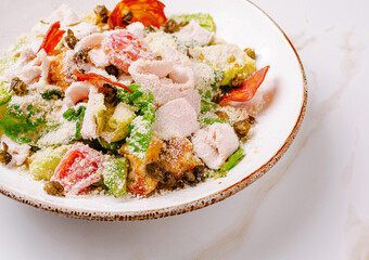 Colorful salad bowl with fresh greens, tomatoes, chicken, and cheese