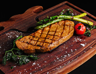 Delicious grilled steak served on a wooden board with fresh vegetables