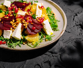 Colorful salad with beets, cheese, and citrus on a textured plate