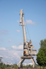 Obraz premium Historic industrial crane stands against a bright blue sky in an urban landscape