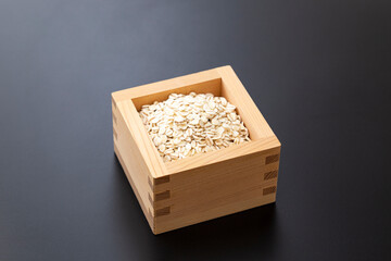 枡に入った押麦　黒背景