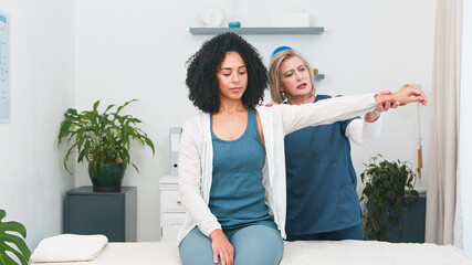 Specialized Senior Physiotherapist Provides Expert Shoulder and Arm Treatment to a Young Black Female Client