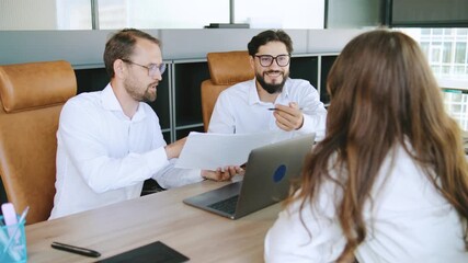 Team members discuss project details in a modern office setting during a business meeting focused on collaboration and strategic planning - Powered by Adobe