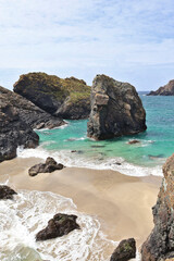 Rocky islands off Kynance Cove, Cornwall surrounded by turquoise blue ocean in summer sunshine; scenic coastal landscape on the Lizard Peninsula with clear ocean waters and rugged cliffs