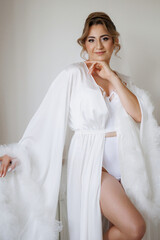 Elegant woman in white robe posing indoors during morning light