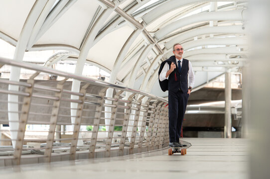 Senior businessman in a suit riding an electric skateboard in the city - Powered by Adobe