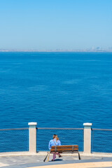 A girl is enjoying a peaceful moment by the calm blue ocean on a sunny day.