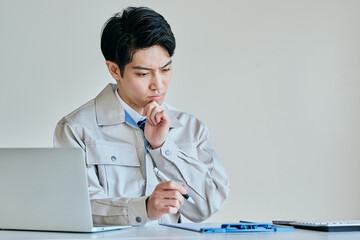 メモをとる作業服姿の日本人男性