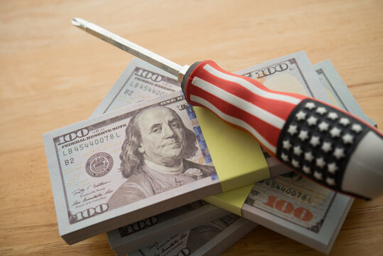 American flag screwdriver on stack US dollar banknotes. Central bank FED (Federal Reserve) change monetary policy to fix economy (inflation, recession, etc.) crisis, global finance and economy concept - Powered by Adobe