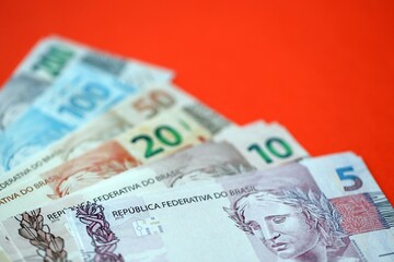 Close up of brazilian reais money bills in big amount on red. Pile of Brazil real currency banknotes