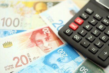 Israel New Shekels banknotes and calculator. The current Israel money bills and calc lies on table