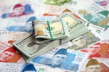 Bunch of US dollar bills lies on big amount of Pakistan rupees banknotes close up