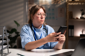 physician nurse using smartphone chatting message working over hours in hospital office on night shift. Medicine and Health care service