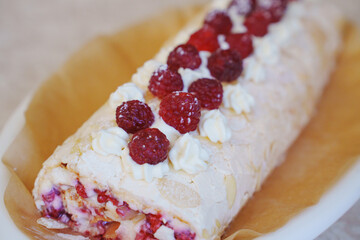 Delicious meringue roll with fresh raspberries and cream on display