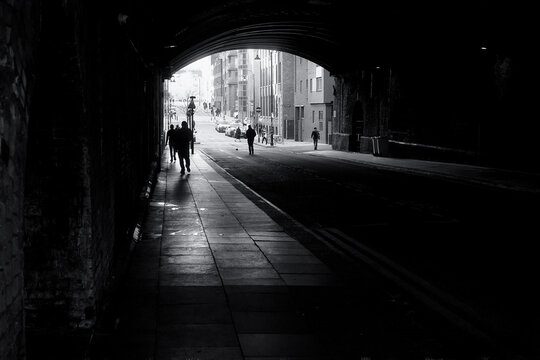 People Walking Under an Old Bridge