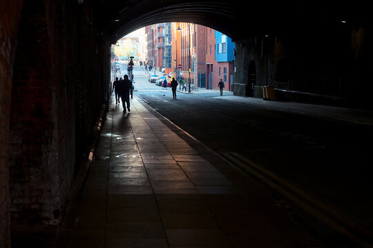 People Walking Under an Old Bridge