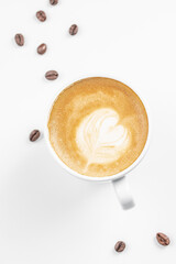 Cup of cappuccino with heart shaped latte art and scattered coffee beans on white background