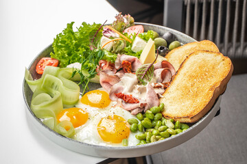 Breakfast plate with fried eggs, toast, ham, cheese, vegetables and fresh salad