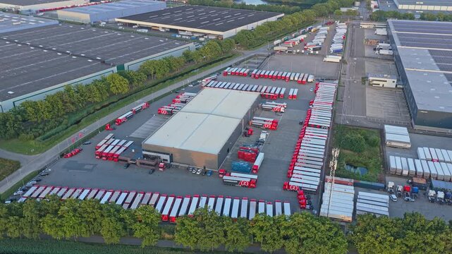 Aerial drone of transport hub and distribution warehouses with trucks at sunset