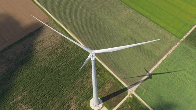 Wide drone panorama of turbines over farmland rows, renewable energy scene