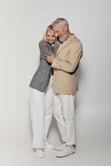 Stylish senior couple sharing a loving embrace in trendy outfits on a bright day
