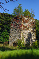 19th-century stone lime kiln in Leszczyniec, Lower Silesia, Poland, stands as an immovable heritage monument with weathered masonry, moss accents, and rustic industrial charm amid verdant surroundings