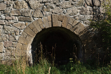 19th-century stone lime kiln in Leszczyniec, Lower Silesia, Poland, stands as an immovable heritage monument with weathered masonry, moss accents, and rustic industrial charm amid verdant surroundings