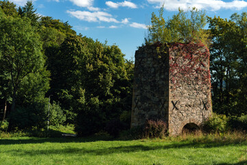 19th-century stone lime kiln in Leszczyniec, Lower Silesia, Poland, stands as an immovable heritage monument with weathered masonry, moss accents, and rustic industrial charm amid verdant surroundings