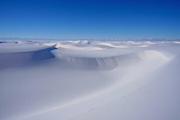 Vast frozen desert landscape under a clear blue sky with rolling snow dunes